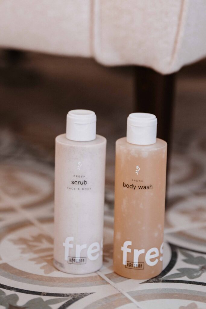 RINGANA FRESH scrub face & body and body wash bottles on a tiled floor