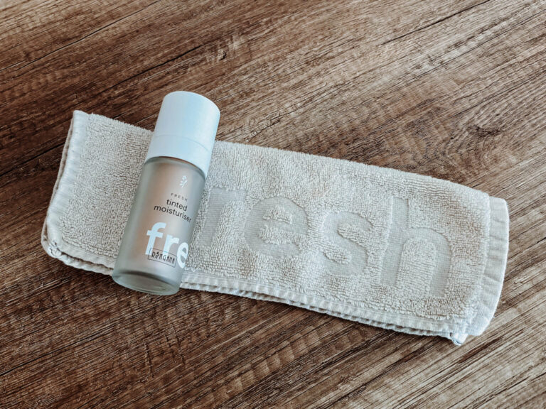 RINGANA FRESH tinted moisturizer bottle on a towel on a wooden surface